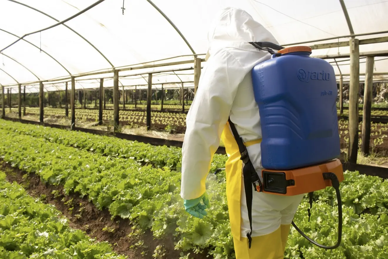 Mujer rociando plantas con una mochila aspersora